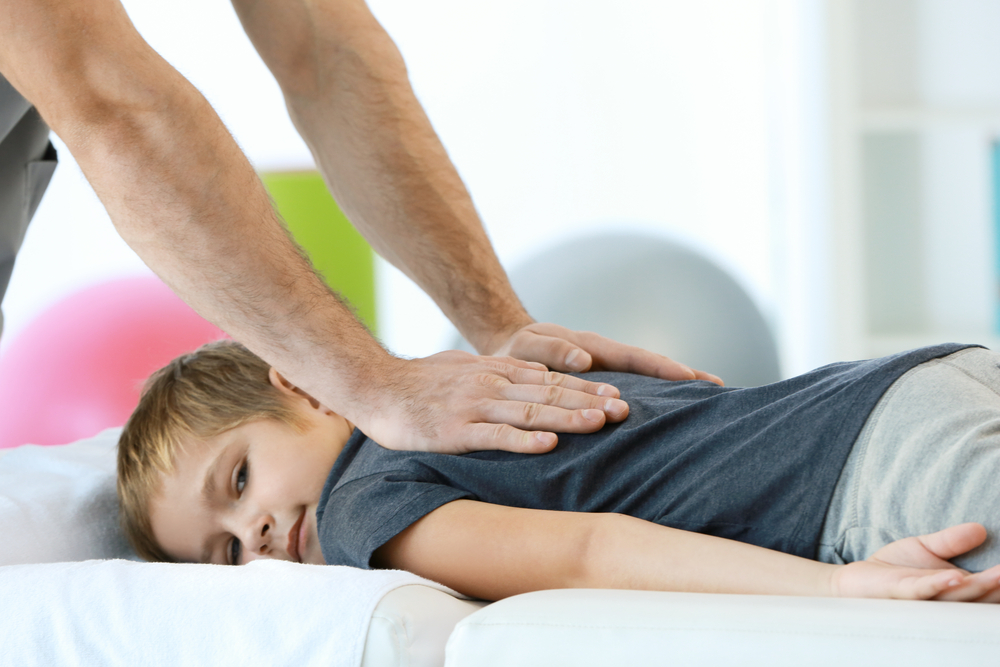 Kid getting chiropractic care for his back pain.